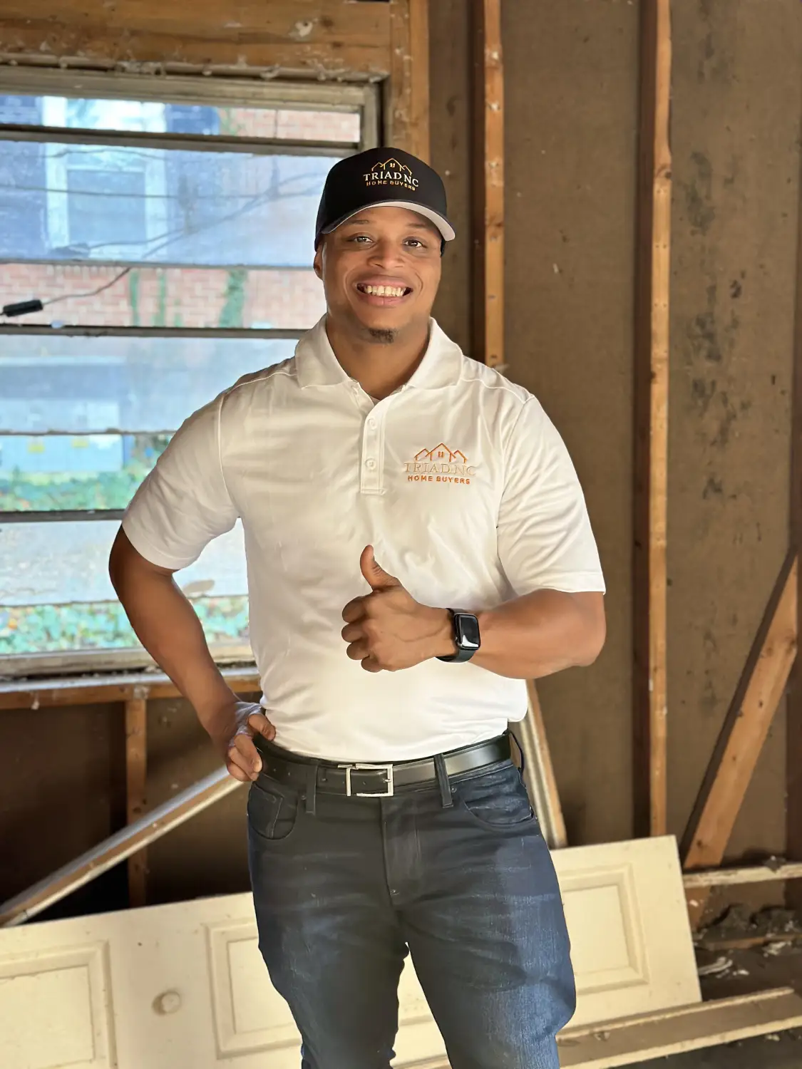 Portrait of a smiling male home buyer in a white shirt giving a thumbs up in a construction setting.
