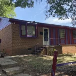 Front view of a red brick ranch-style house with a small front porch and concrete steps.