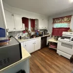 Interior view of a cluttered residential kitchen with a messy countertop and outdated appliances.